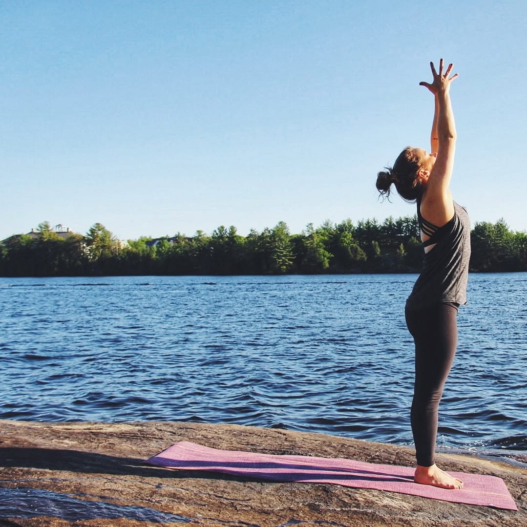 Danielle practicing yoga on a rock by a lake